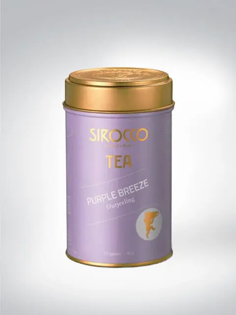 Goldene Teedose von Sirocco mit lila Etikett, beschriftet mit Purple Breeze Darjeeling. Organischer Tee in edler Verpackung.